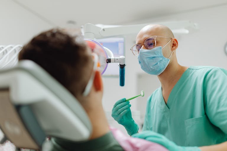 Dentist examining a patient's teeth with focus on tools in a well-lit clinic.