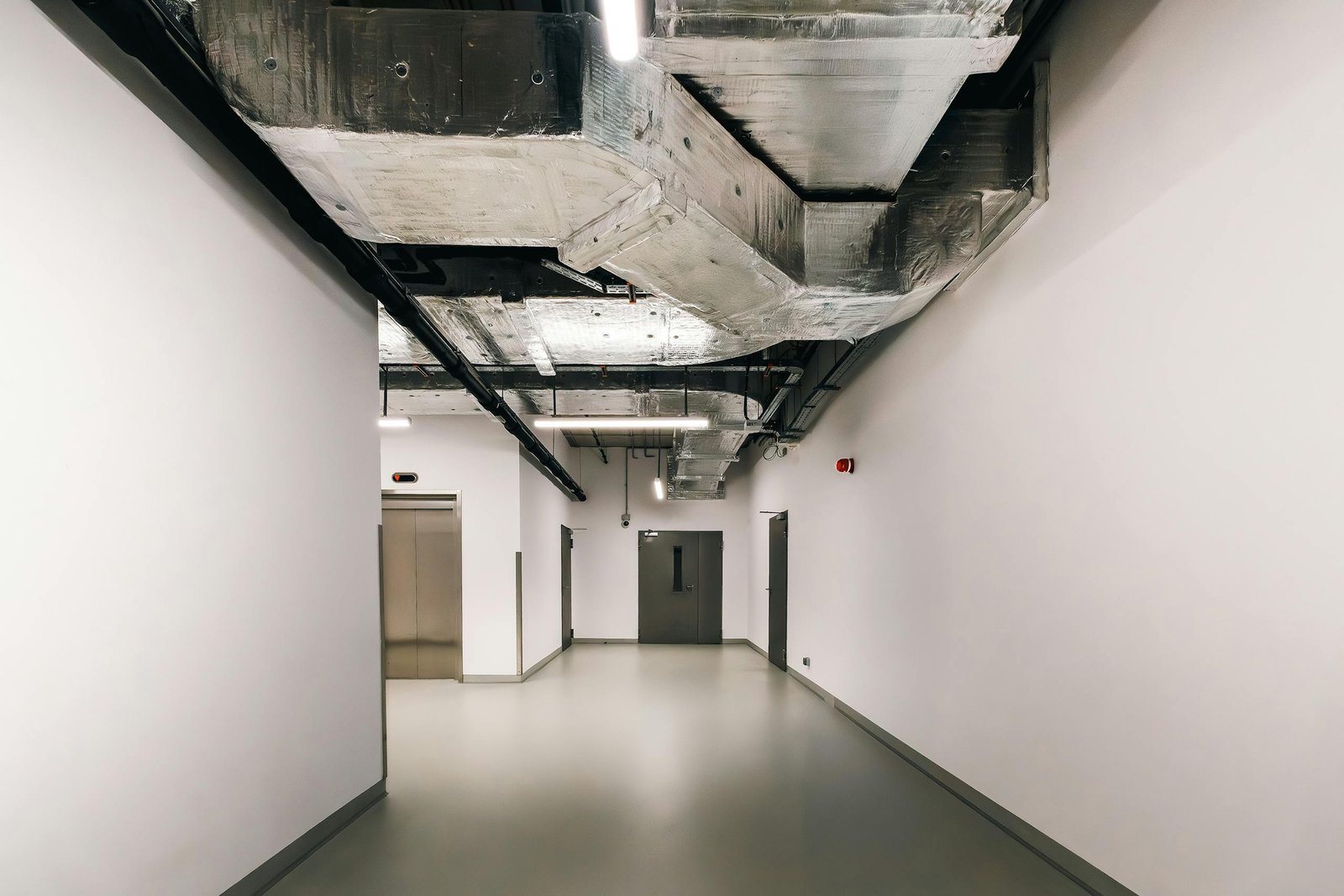 Spacious industrial hallway featuring exposed HVAC ductwork and modern design elements.