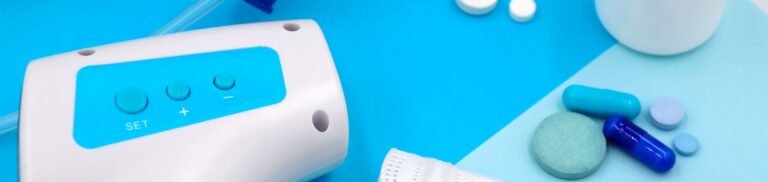 A collection of medical supplies including pills, a mask, and a thermometer on a blue surface.