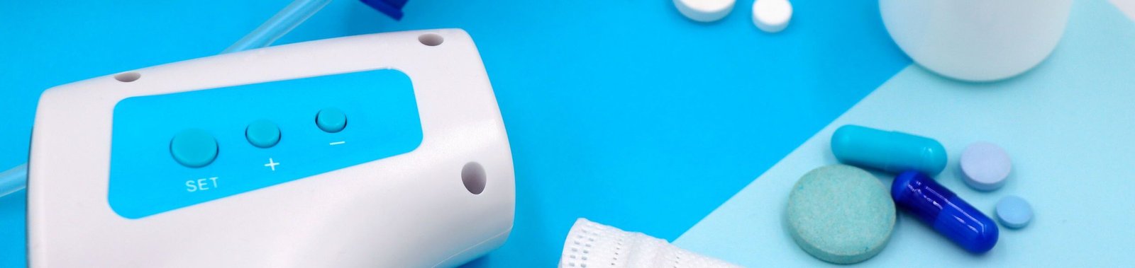 A collection of medical supplies including pills, a mask, and a thermometer on a blue surface.
