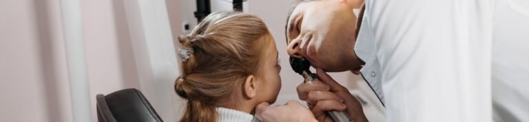 A doctor examines a young girl's ear during a medical appointment in a clinic.