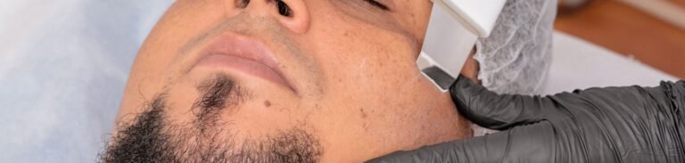 A man undergoing a facial treatment with advanced cosmetology equipment.