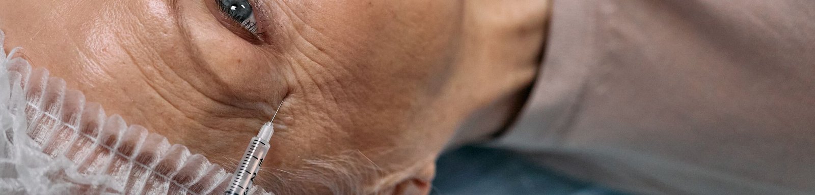 A senior woman undergoes a cosmetic injection procedure in a medical facility.
