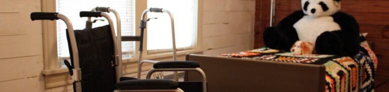 A warm bedroom featuring a wheelchair and plush panda, symbolizing comfort and accessibility.