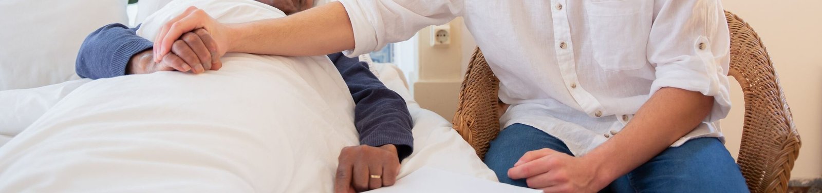 A young man comforts an elderly man in bed, foster warmth and care.