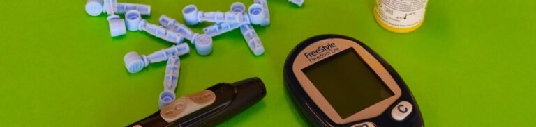 Essential diabetes equipment including glucometer and lancets on a green backdrop.