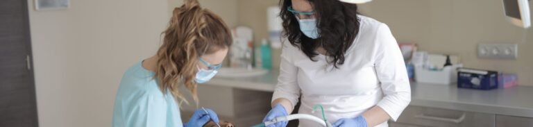 Female dentists in medical masks and latex gloves wearing uniform using medical instruments while treating teeth of female patient in modern dental clinic